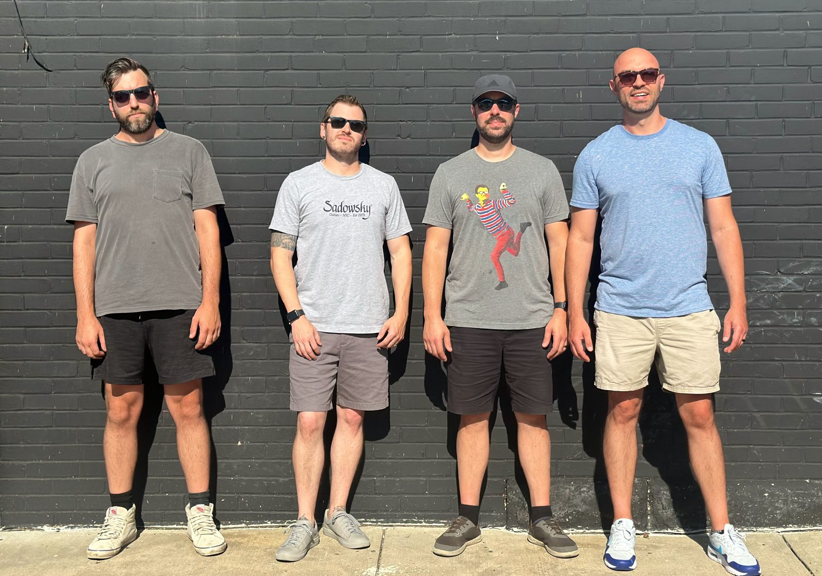 The full band against a black brick wall