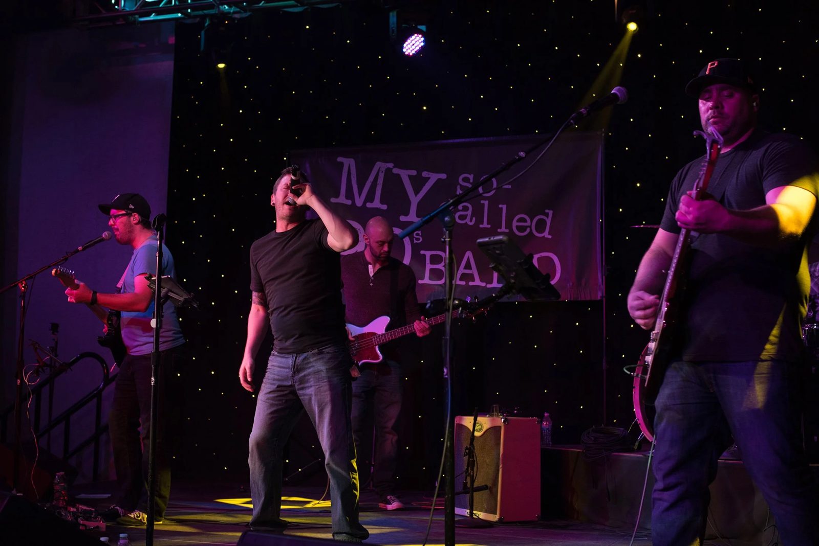 The band on stage with purple and yellow lighting